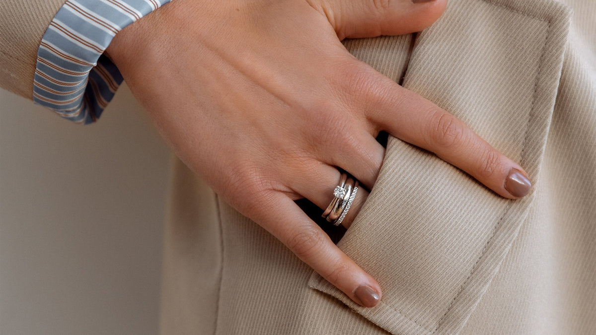 Hand waarop een verlovingsring met trouwring is te zien.